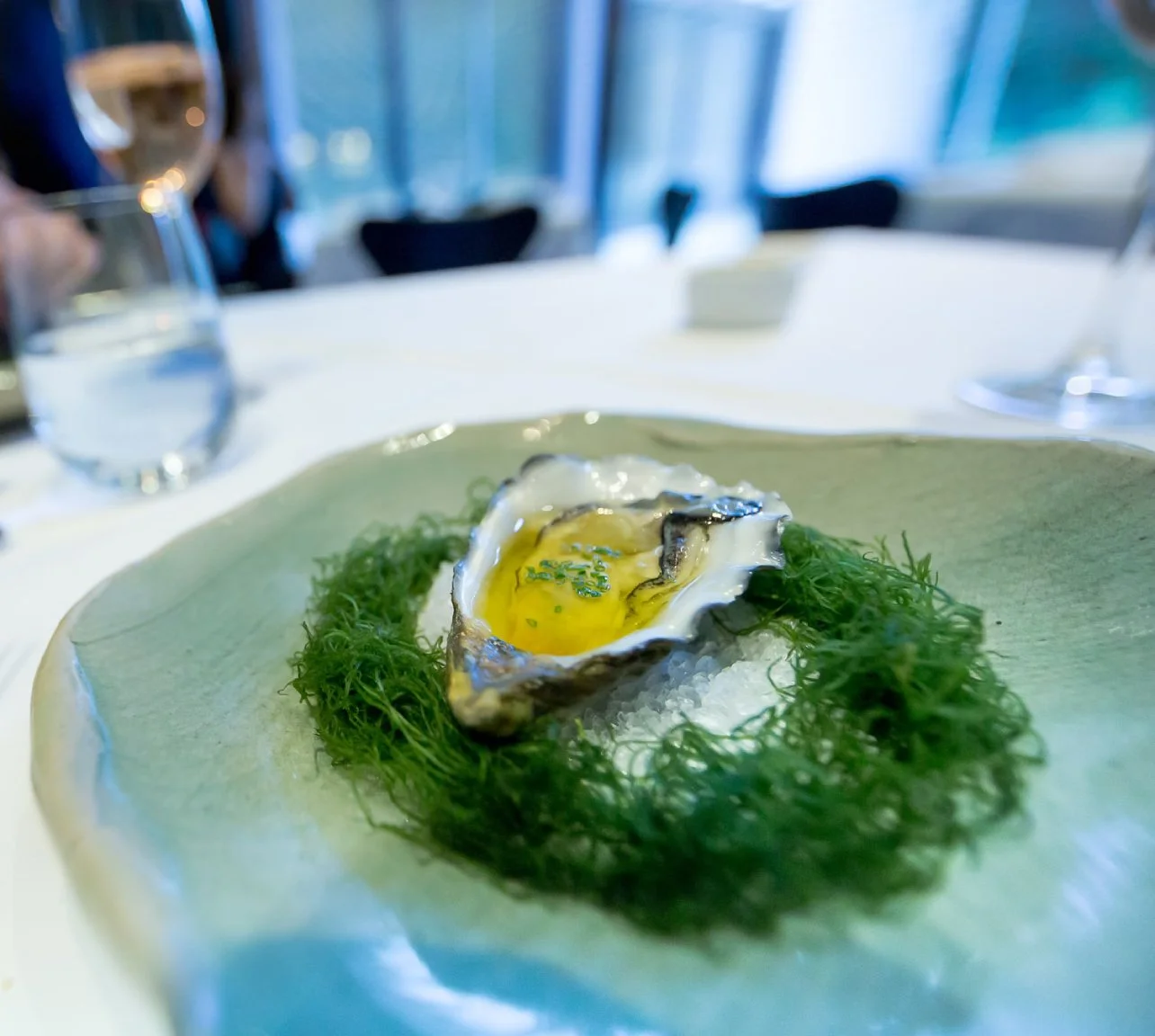 Fine-dining presentation of an oyster with chili oil, served on a bed of sea salt and fennel, at a restaurant in Sydney, Australia.