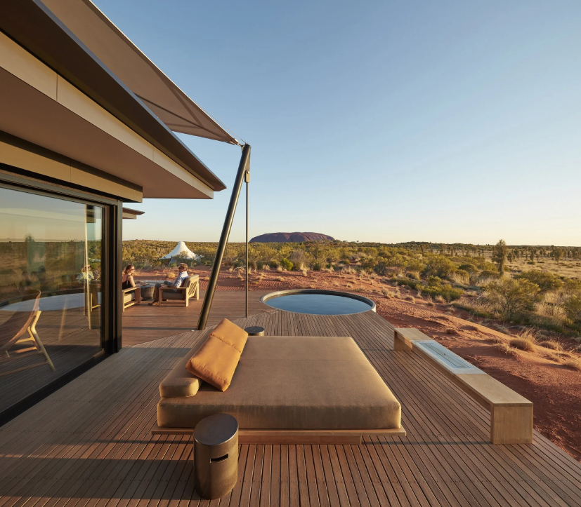 A private outdoor deck with a daybed and small plunge pool overlooking the red desert landscape near Uluru.