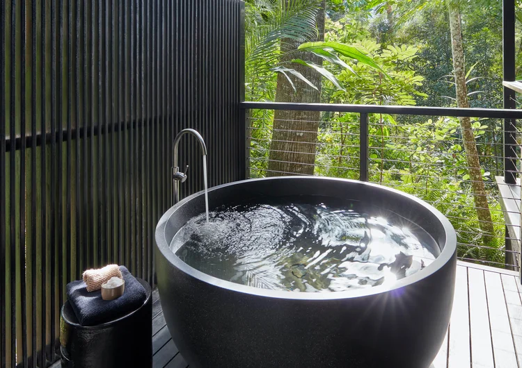 A luxurious private bathing experience at Silky Oaks Lodge in the Daintree Rainforest, Queensland, Australia, featuring an open-air tub overlooking the tranquil river and surrounded by lush tropical greenery.