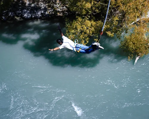 Person slipping and falling into a river while tied to a harness and rope.