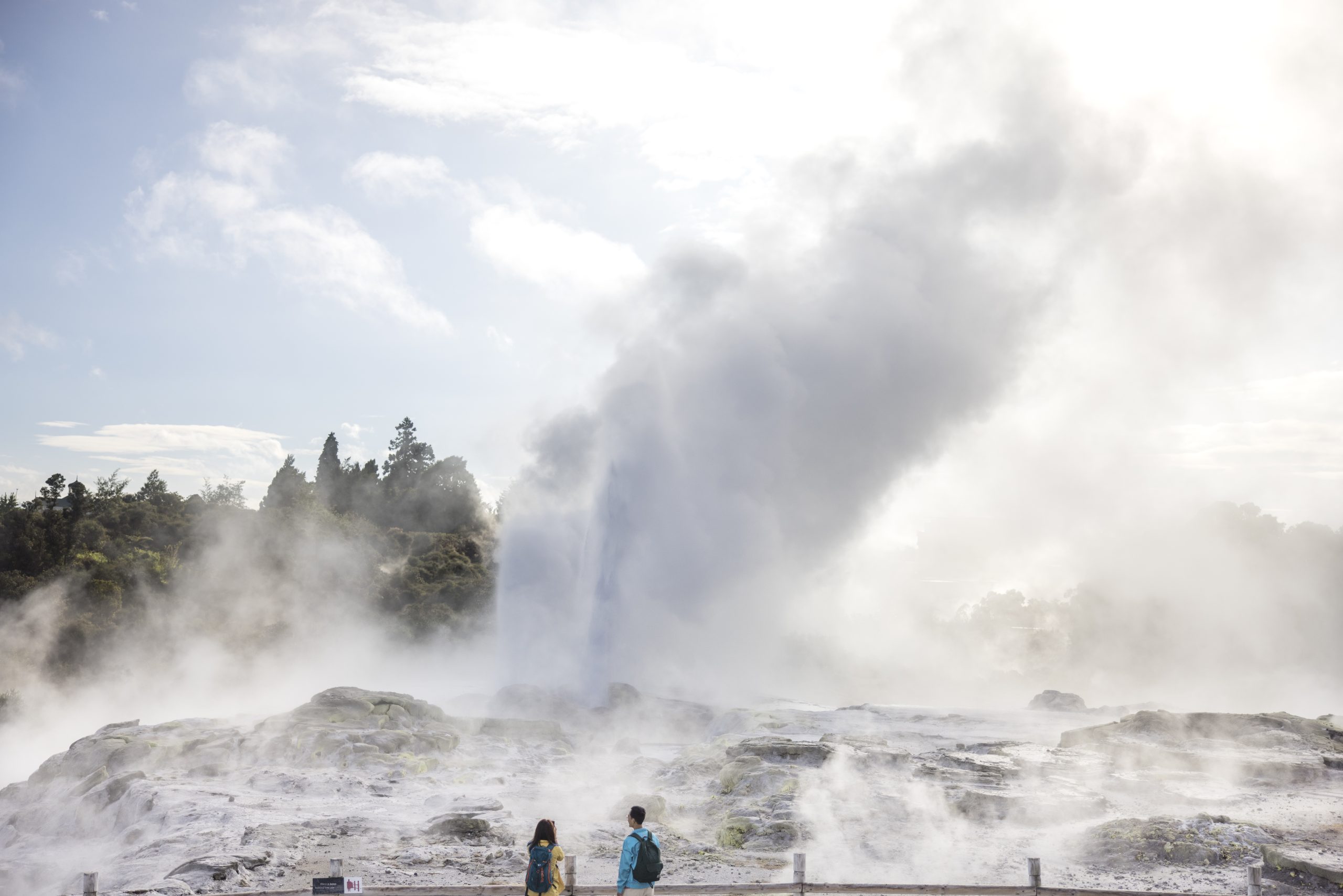 Two travelers stand watching geothermal activity, Bay of Plenty, Rotorua.