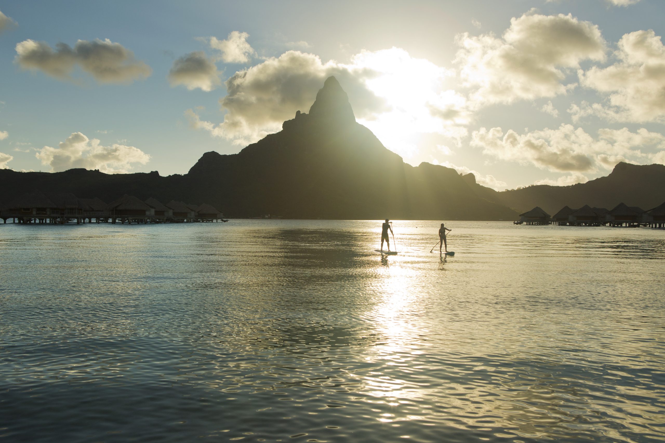 Stunning view of two paddle borders, behind them there is a mountain rising from the sea, Bora Bora.
