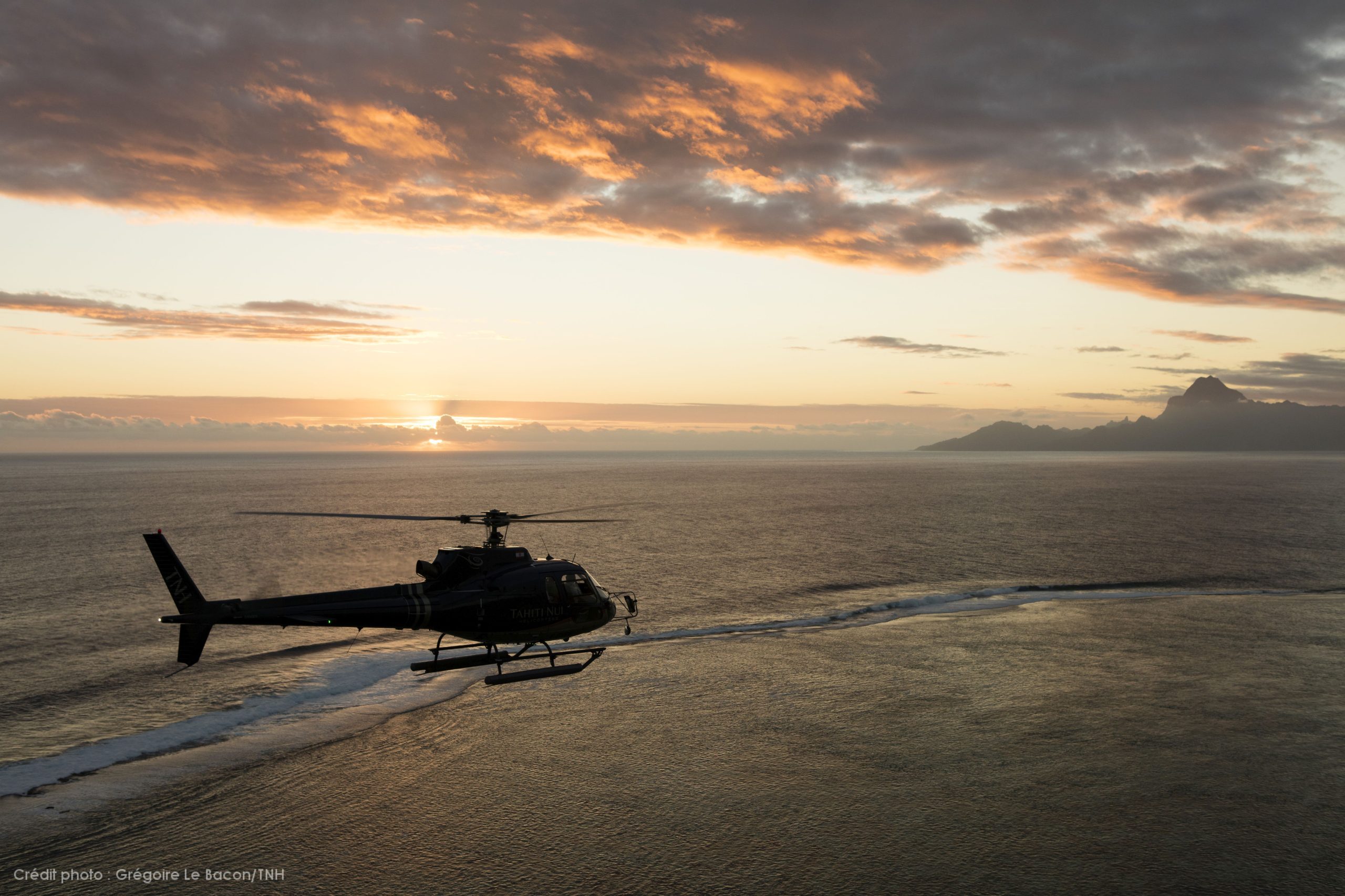 Helicopter flies over Moorea at sunset