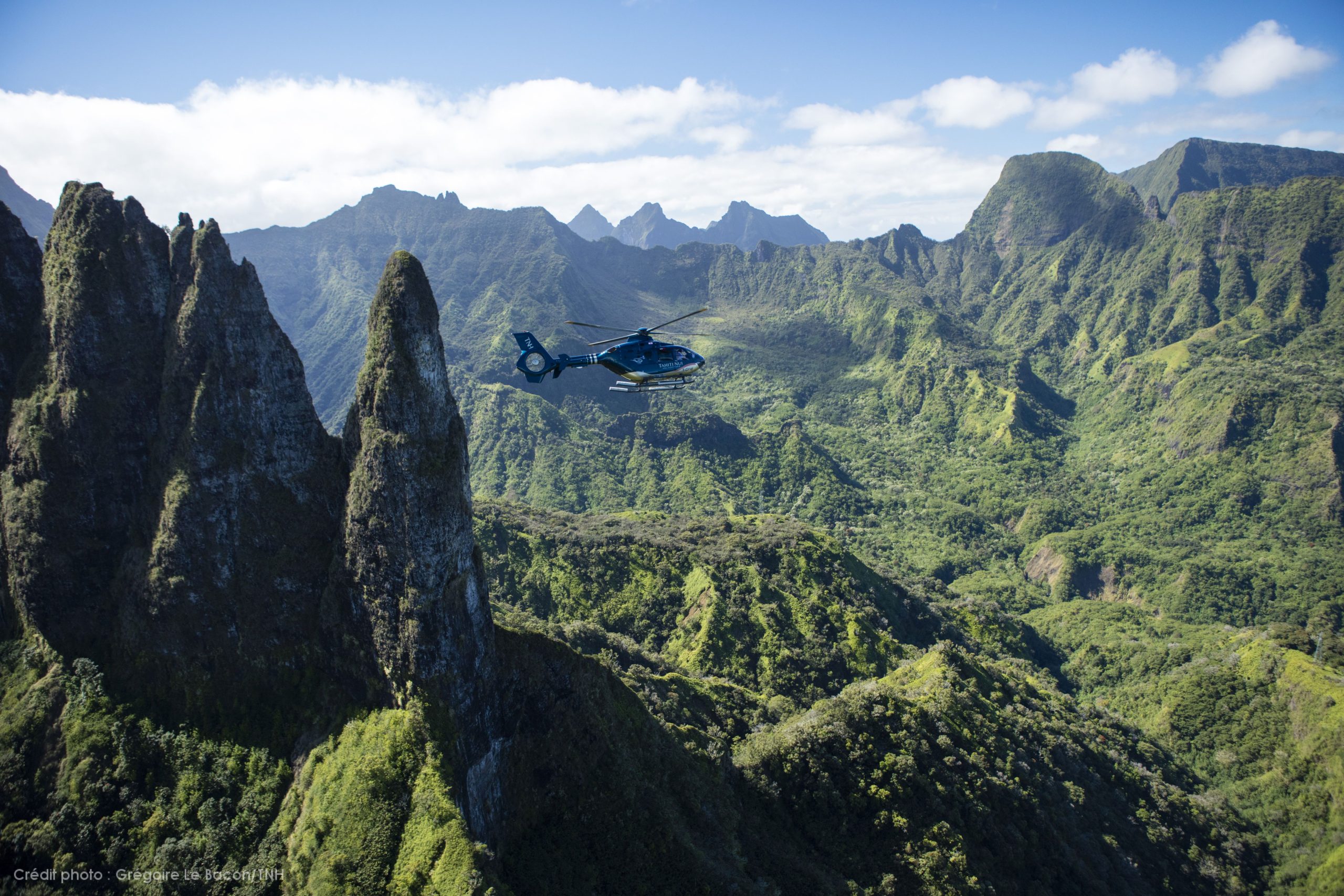 Landscape view of helicopter flying through a stunning green mountain range in Moorea, Society Islands