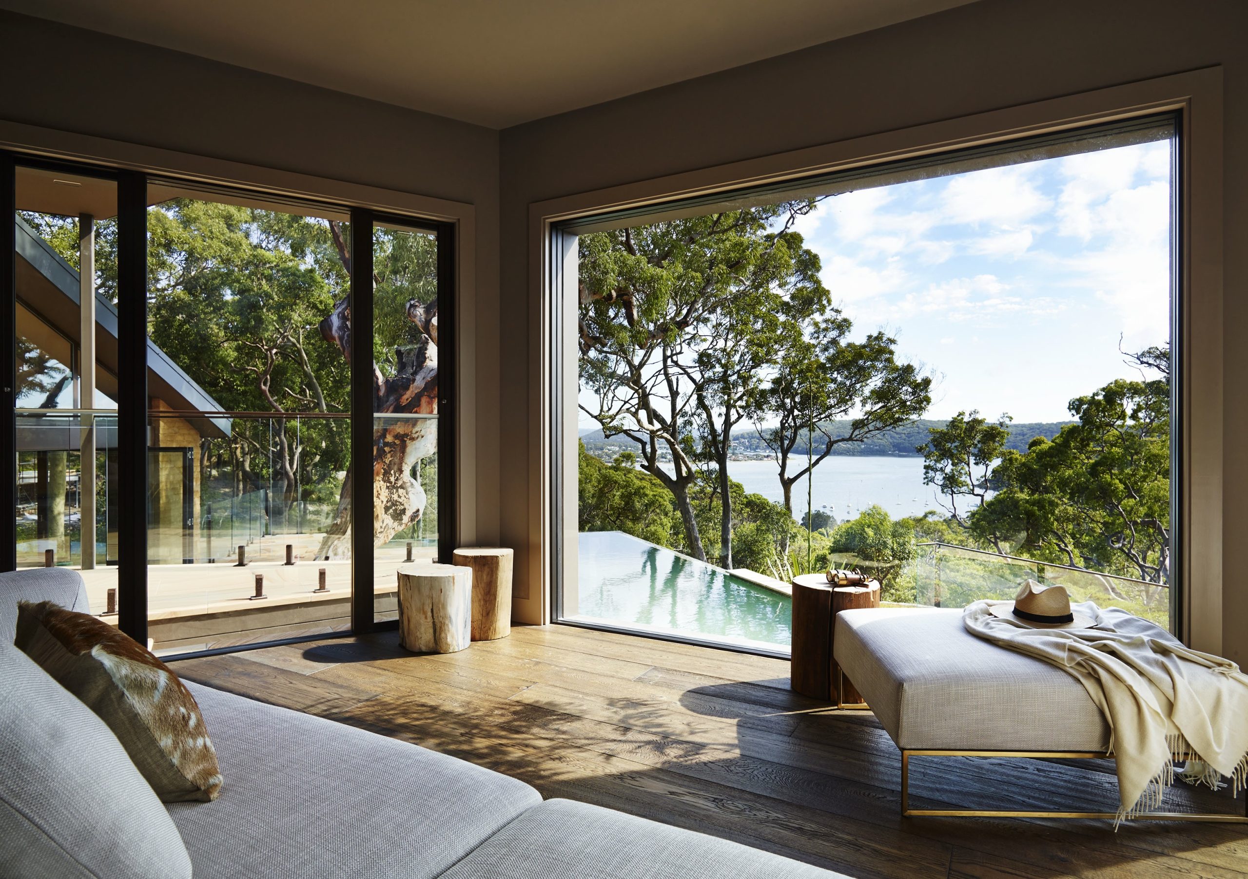 Interior of room at Pretty Beach House in New South Wales. A couch overlooks a private pool and stunning view of the ocean