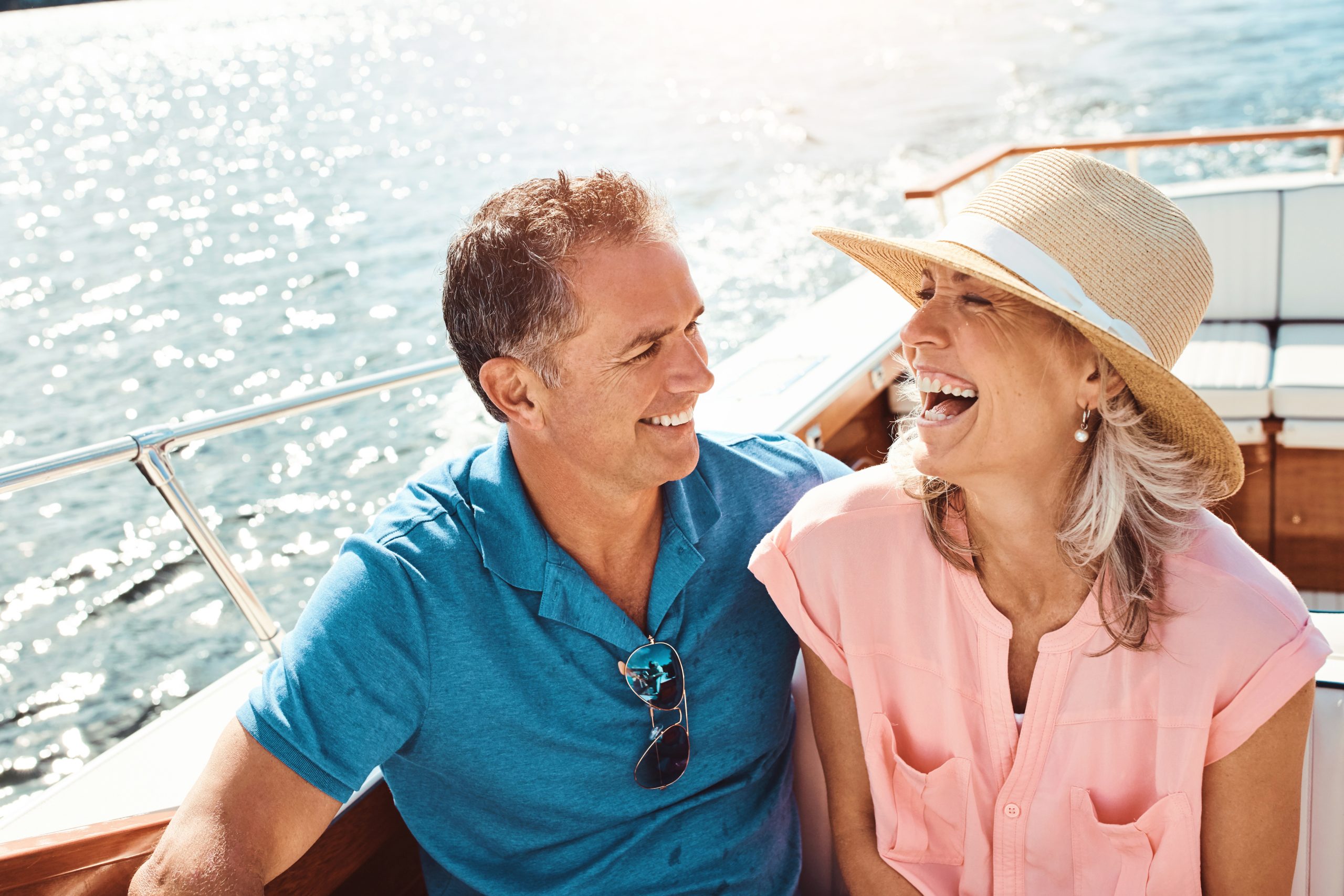 A couple seated at an outdoor table at a winery in Adelaide, Australia, smiling and enjoying a private wine tasting with glasses of red and white wine, surrounded by vineyard views and natural scenery.