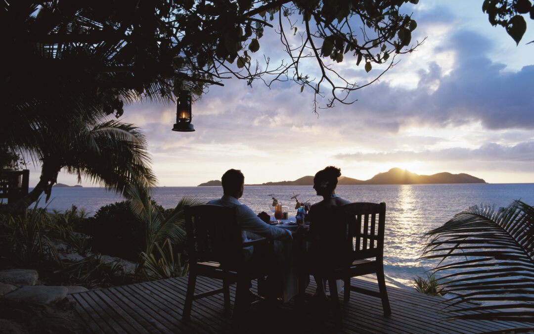 A couple enjoys a cocktail together on the deck of their adults-only resort in Likuliku.