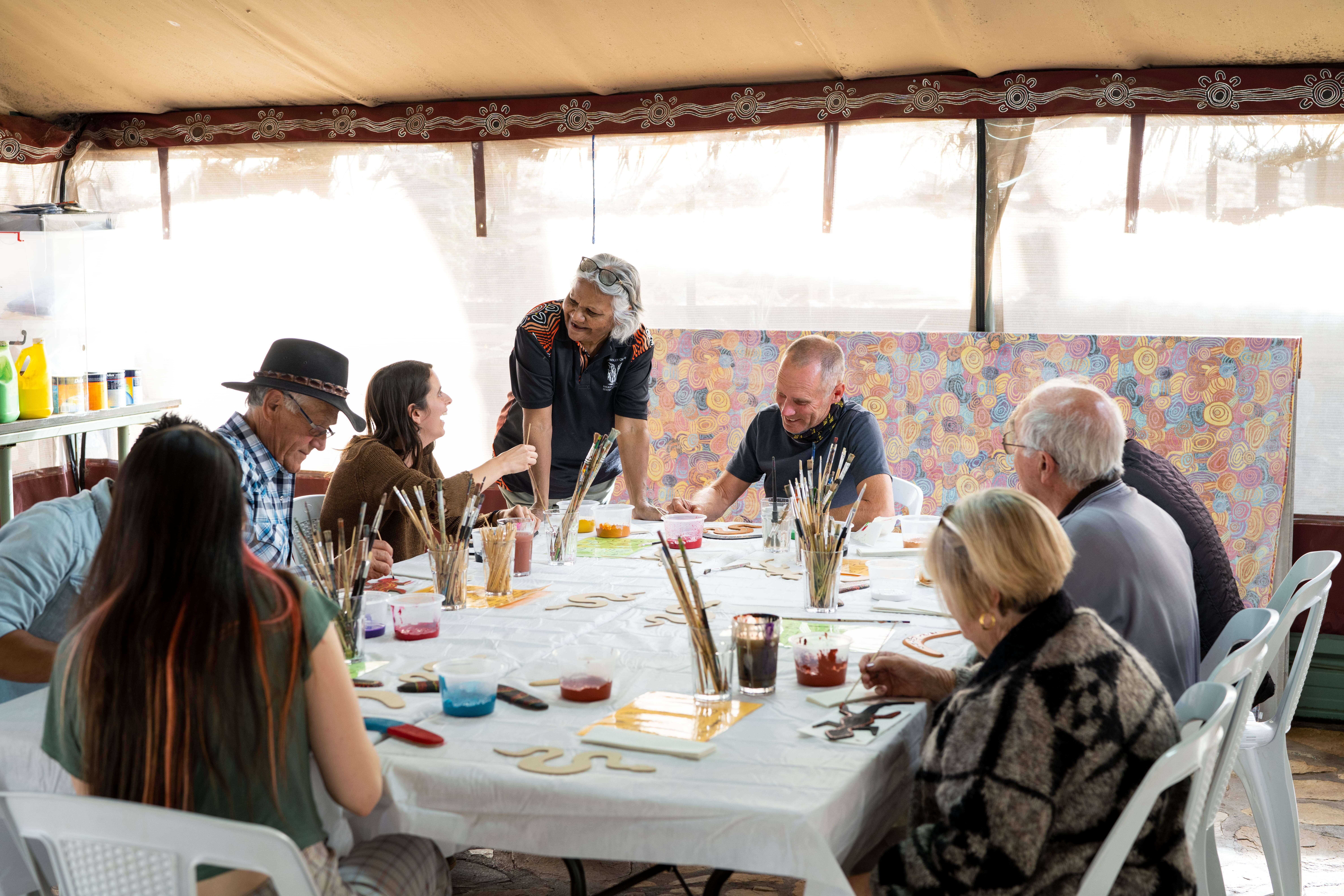 Senior tour group crafts their own souvenir in a dot painting workshop, learning the traditional techniques and significance behind them in Western Arrernte artwork.