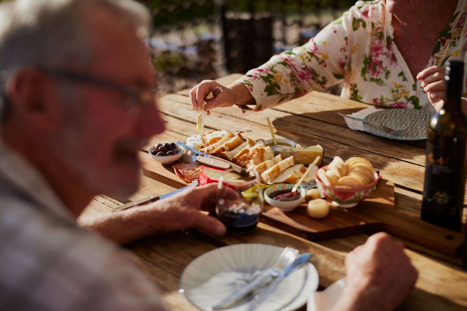 Close-up of a shared meal and wine at an outdoor table in an Australian wine region vineyard setting.
