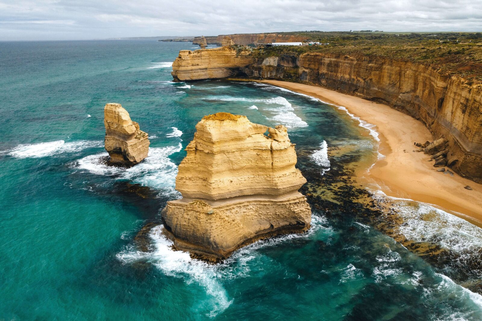 Aerial view of the limestone sea stacks of the Twelve Apostles rising from turquoise ocean waters along Victoria’s Great Ocean Road.