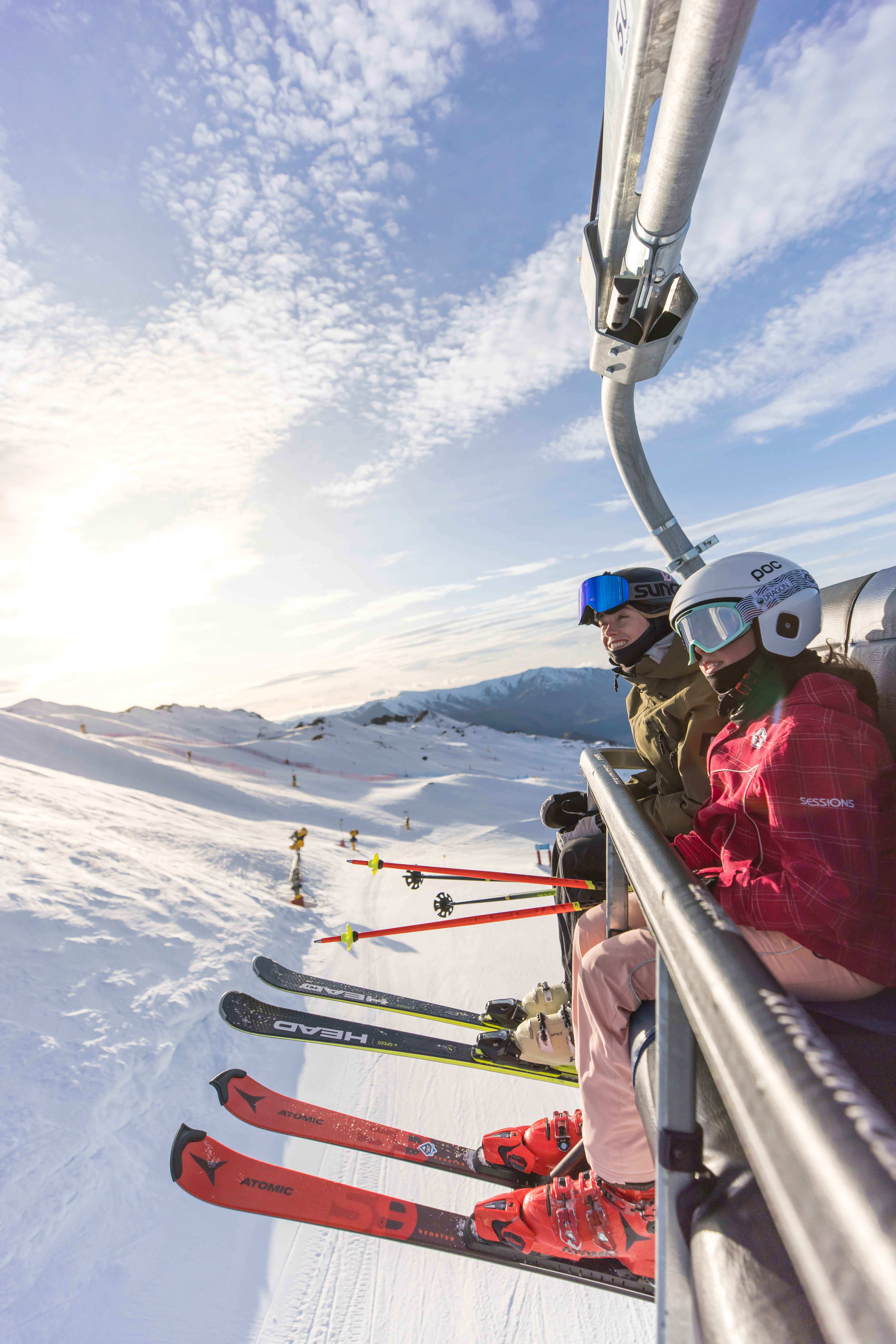 Two young skiers ride the lift at a ski resort in Coronet Peak, Queenstown.