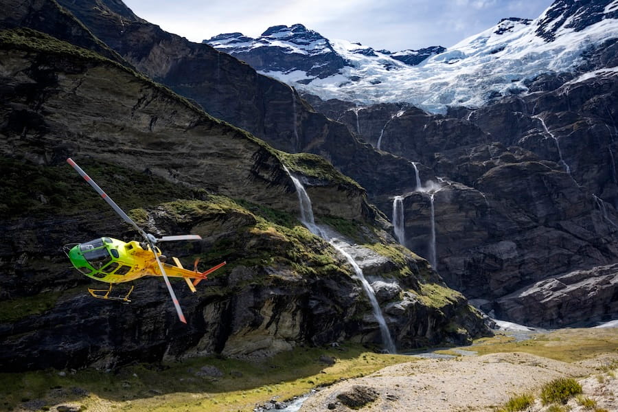 Heliworks private helicopter hovers above the ground, making a landing at Earnslaw Burn, New Zealand.
