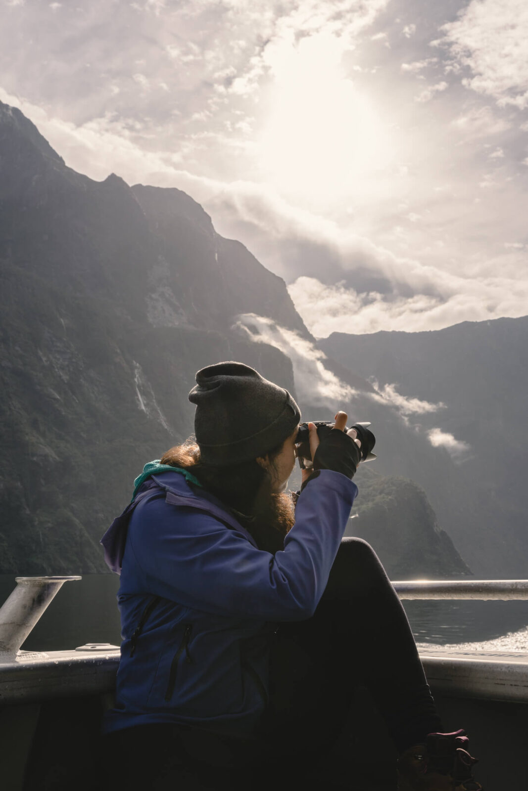 Woman taking photos with camera on a cruise on Milford Sound. Fiordland National Park, New Zealand.