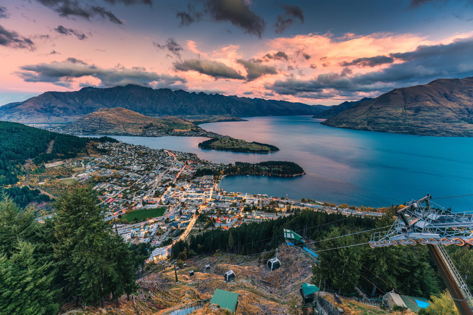 Aerial view of Beautiful sunset sky over illuminated Queenstown with Lake Wakatipu and Skyline Gondola at New Zealand.