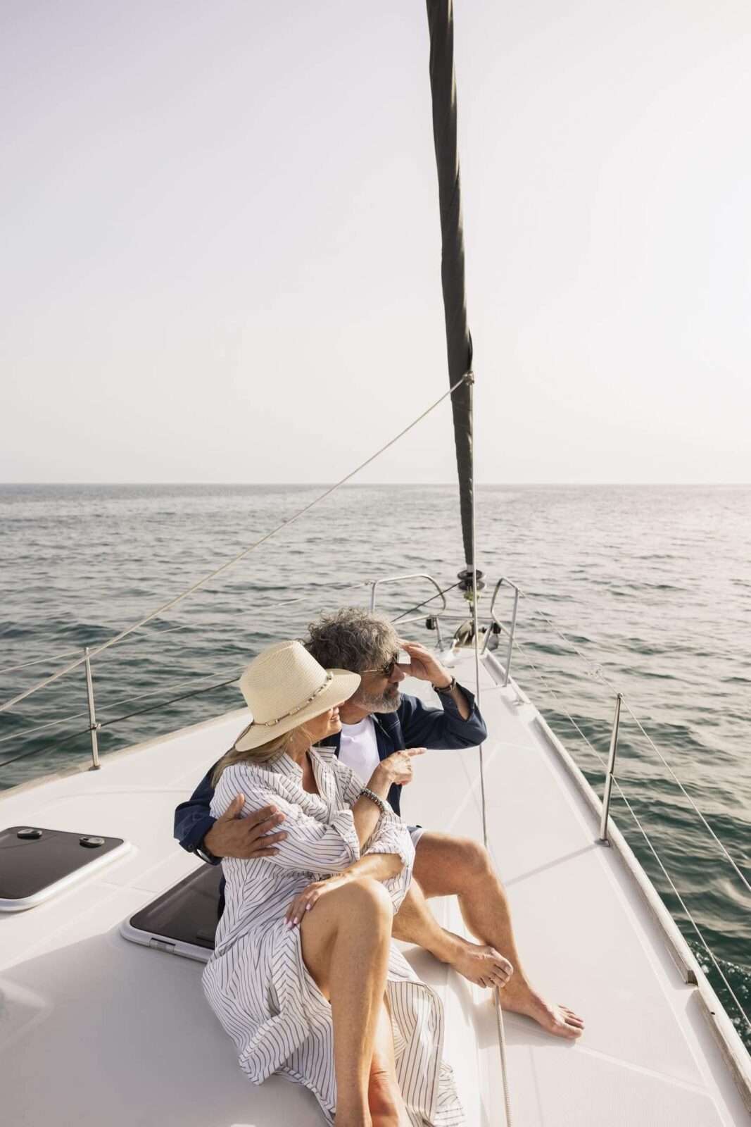 Mature couple relaxing on a sailboat deck, looking out at the ocean together.