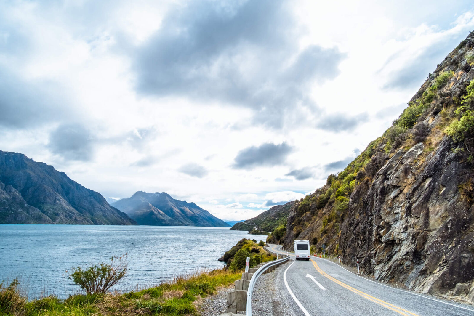 The stunning landscape of road beside the ocean with a cloudy and mountain scene.